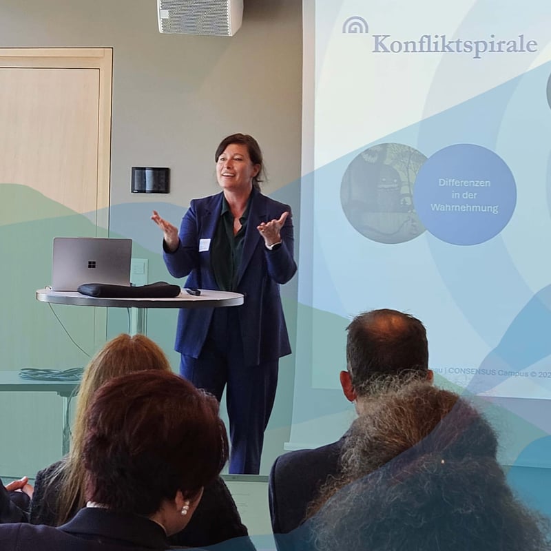 Trainerin erläutert im Seminarraum Methoden der Mediationsausbildung bei CONSENSUS Campus