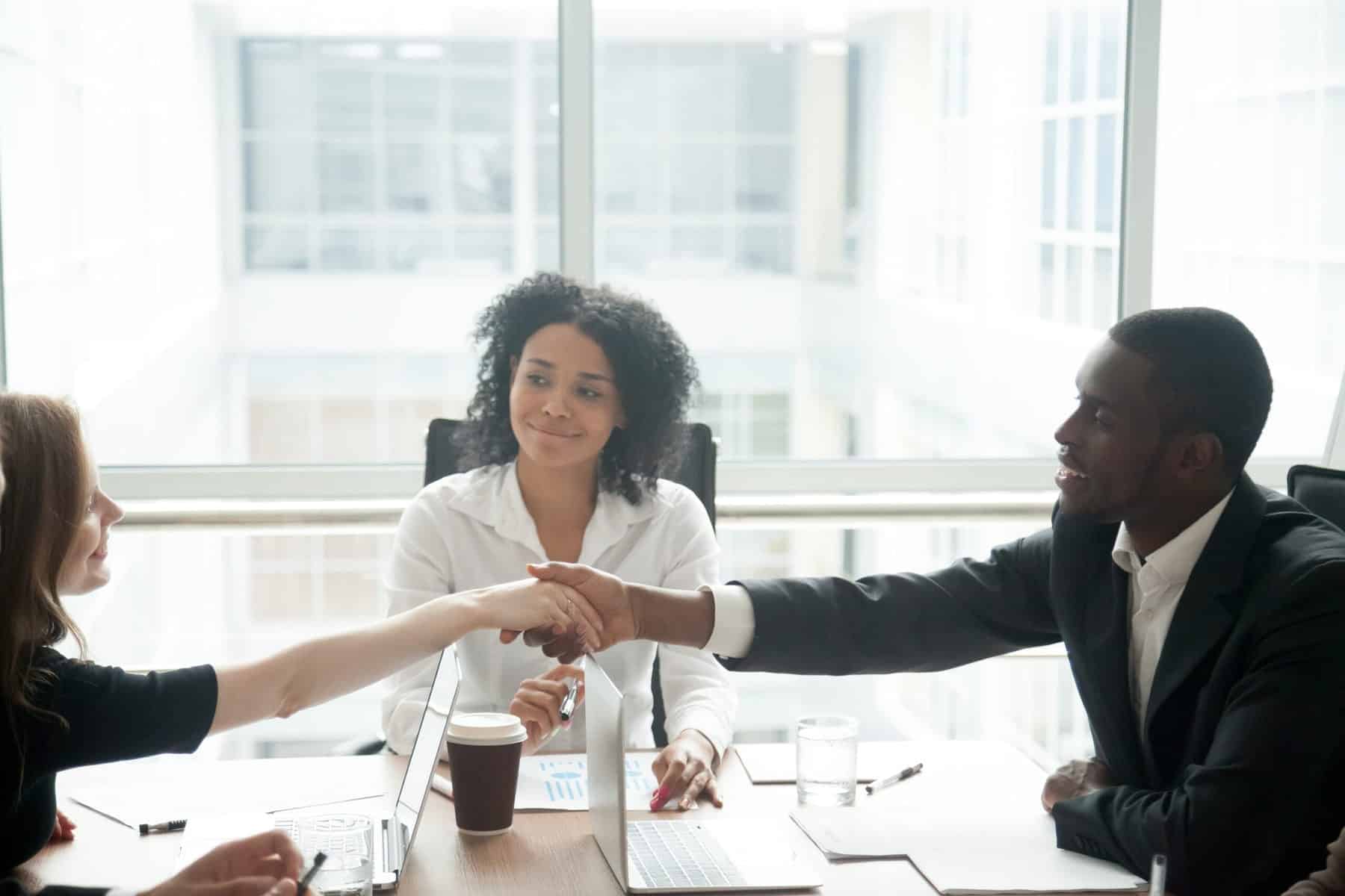 Smiling african businessman handshaking greeting caucasian busin